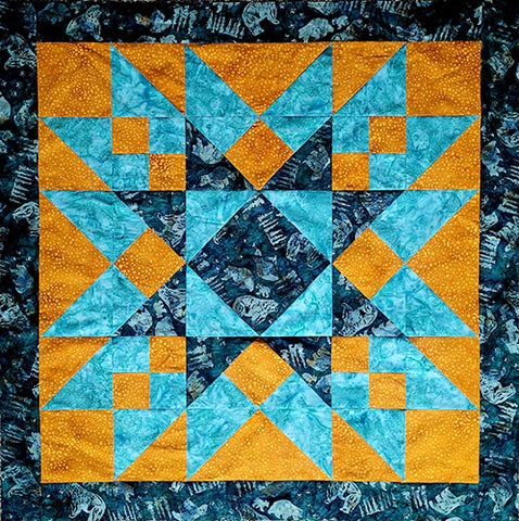 A radiating star quilt block with blue and brown geometric pattern on a textured background