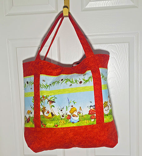 This quilted cotton tote features fun gnomes doing their thing and red mushrooms and birds along with red handles and accents. back
