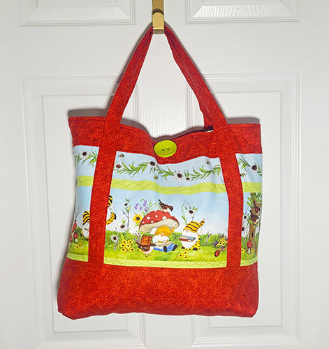 This quilted cotton tote features fun gnomes doing their thing and red mushrooms and birds along with red handles and accents. Front