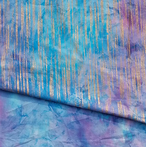 Roll of fabric with blue and purple watercolor pattern and gold metallic vertical stripes