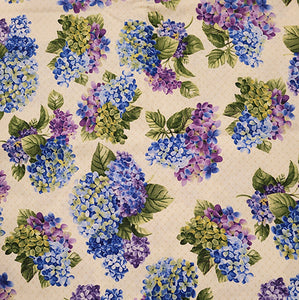 This fabric features clusters of hydrangeas in shades of blue and purple on a cream background.