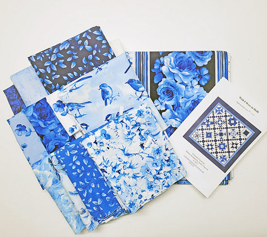 Image shows the kit's quilt pattern along with various blue and white fabrics featuring flowers and birds