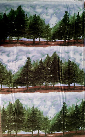 This border stripe fabric features rows of large evergreen trees below a wintery sky.