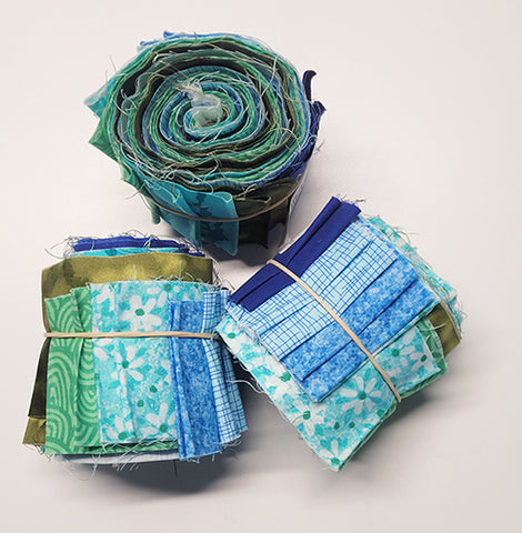 Strips of fabric -blues and greens-rolled up into a cylinder shape