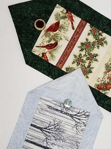 Two table runners for the holidays.  One has cardinals and green borders while the other has silver trees with blue borders.  Both fabric kits are available at Colorado Creations Quilting