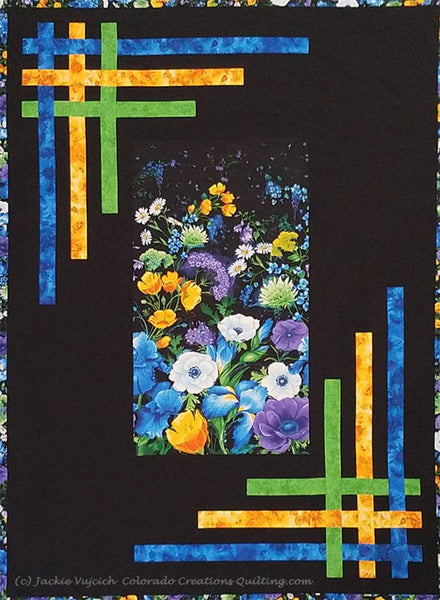 Quilt center of blue, green, and purple flowers on a background of black with yellow, blue and green strips woven in the borders.  Pattern available at Colorado Creations Quilting