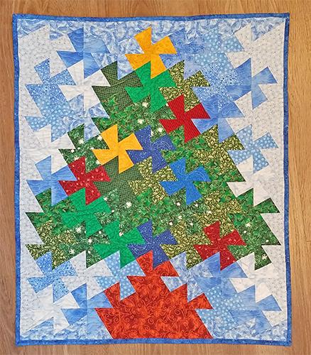 Just in time for the holiday season, this one of a kind quilted wall hanging features a Christmas tree with ornaments and a star on top on a blue background Available at Colorado Creations Quilting
