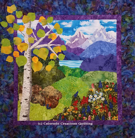Colorado Escape landscape quilt pattern shows purple mountains in the distance with green rolling hills and wildflowers and an aspen tree in the foreground by Colorado Creations Quilting