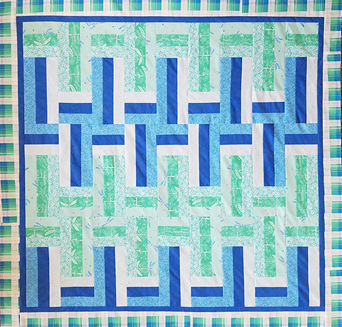 Quilt done in with alternating rectangles in blues and light greens.