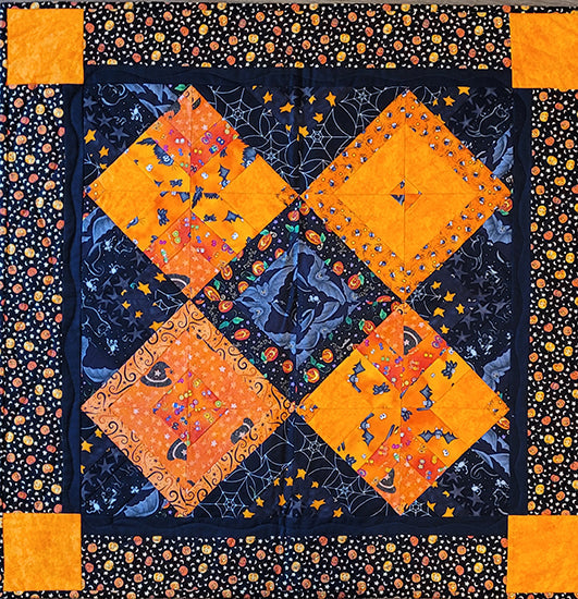 This quilt features black and orange squares on point in fabric with Halloween images. Designed by Jackie Vujcich, this wall quilt measures approximately 30"W x 30"H. 