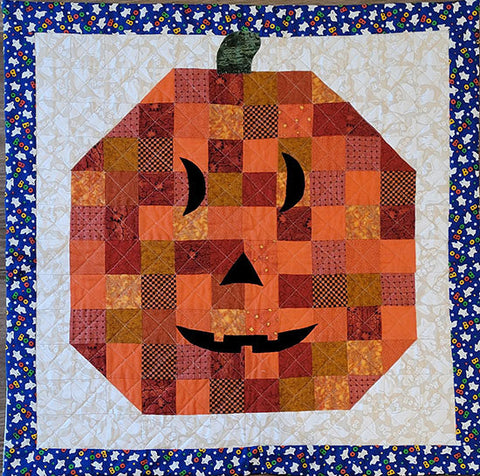 This quilt features a pumpkin face done in little 2" squares in shades of orange with a smiling toothless face. The background is cream with floating ghosts. Designed by Jackie Vujcich, this wall quilt measures approximately 27"W x 27"H. 