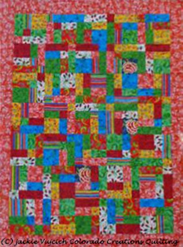 This hand quilt features fabric squares and rectangles in shades of pink, green and more! It used Kaffe Fasset fabric. Designed by Jackie Vujcich, this quilt measures approximately 48" x 64". The name comes from using fat quarters to create the quilt.