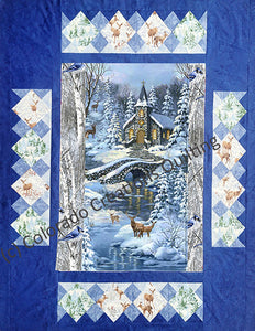 This pattern features a central panel with a cobble-stone bridge over a river and a snow-covered country church with yellow lighting in the distance. Wildlife like deer surround the snowy evergreen trees.  Multiple borders span outward from there featuring trees and deer blocks set on point. Kit and pattern available at Colorado Creations Quilting 