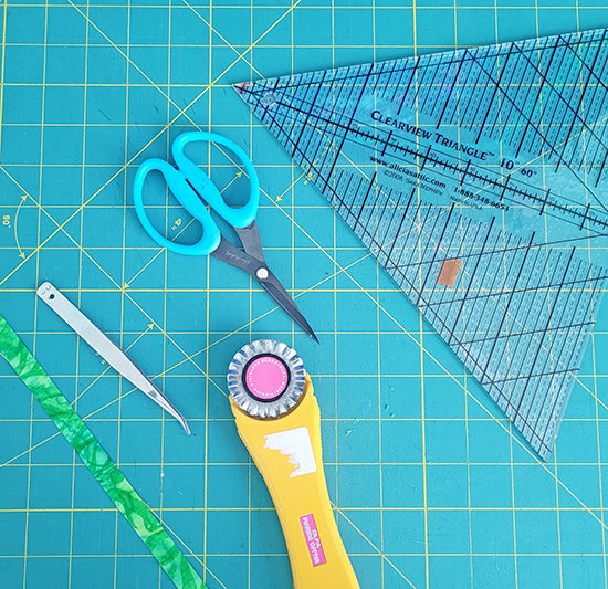 Image of sharp applique scissors, triangular ruler, rotary cutter and tweezers use to make the carrot