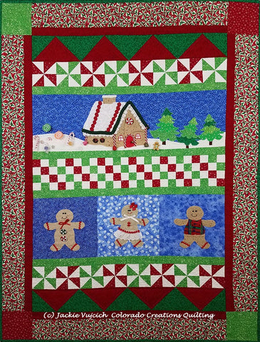 Sugar & Spice row quilt in pieced blocks of red/green/white and appliques of gingerbread people and houses on a blue background available at Colorado Creations Quilting