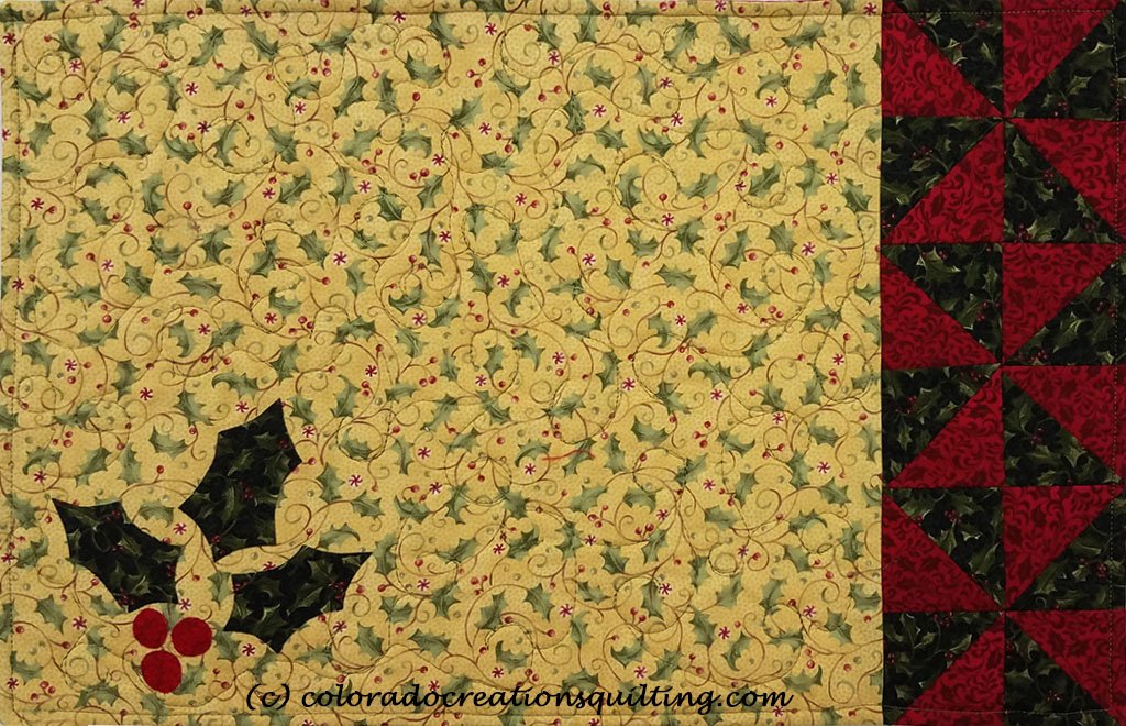 Cream colored placemats with holly leaves applique and green and red triangles on one edge