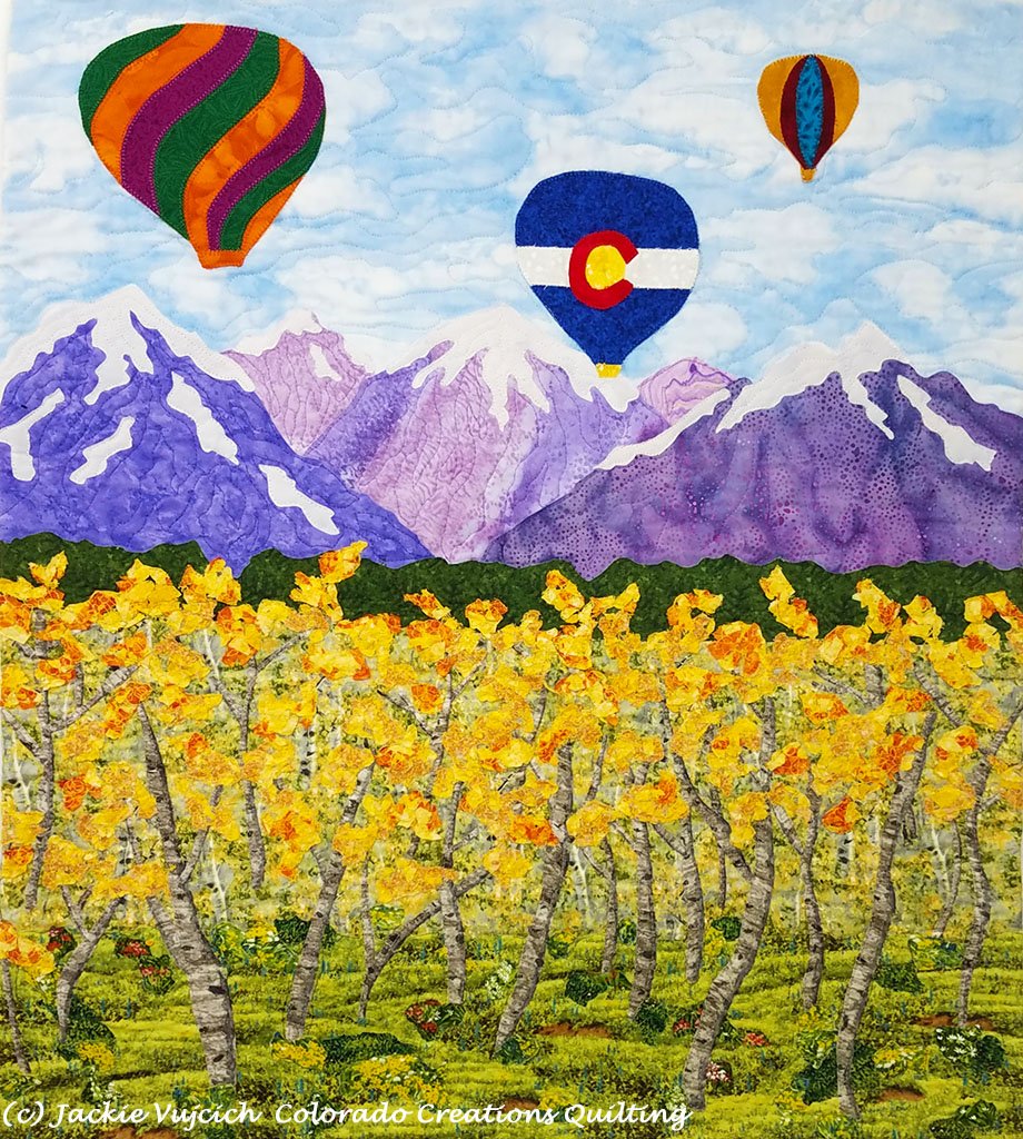 Soaring Over the Rockies Quilt shows 3 hot air balloons flying over snowcapped mountain peaks.  Aspens turning yellow are in the meadow below. Available at Colorado Creations Quilting