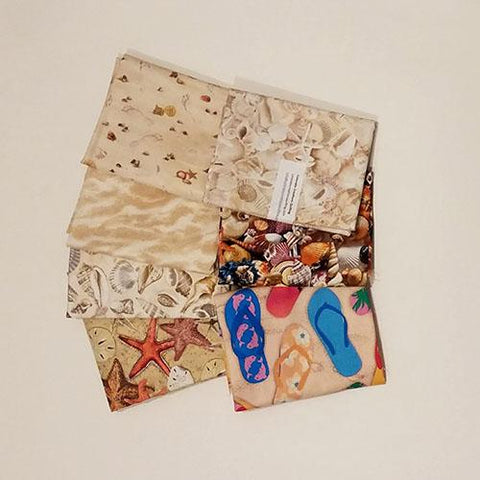 This fat quarter bundle has a selection of seashells and sand fabrics 