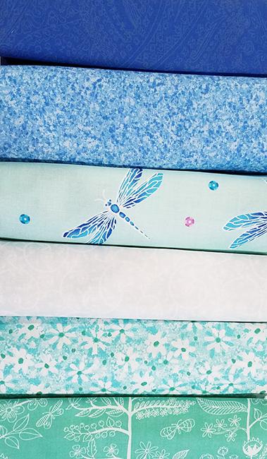 A 6-Pack is six coordinated half-yard pieces of fabric. This particular kit is called Dragonflies & Daisies. It includes shades of blue and mint green fabric.