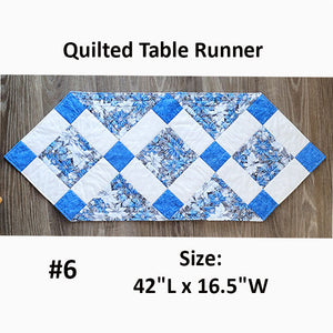 This quilted runner has diamonds on point in metallic winter prints of dark or light blue. Designed by Jackie Vujcich.