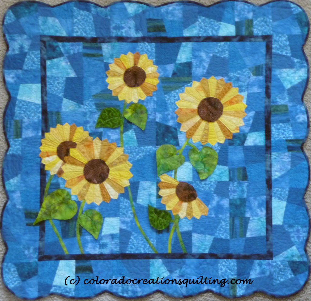 Quilt shows appliqued dresden plate sytle sunflowers on a blue background