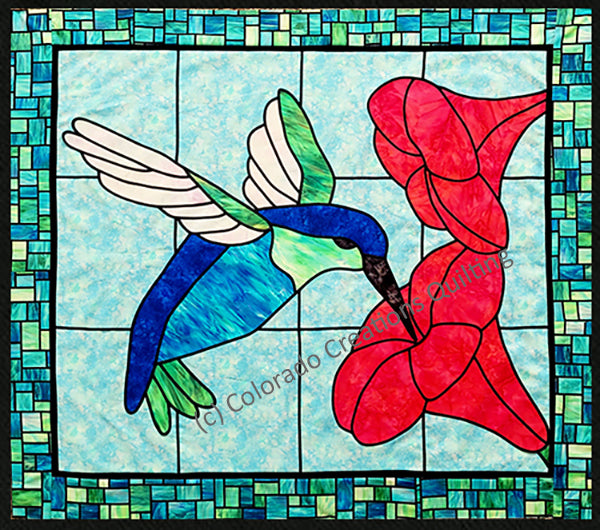 The beautiful hummingbird is gathering nectar from the center of vibrant flowers in stained glass style.  Pattern available at Colorado Creations Quilting